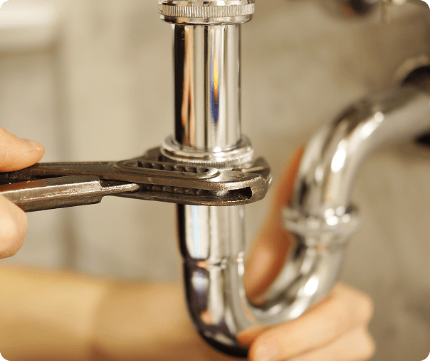 Plumber tightening a chrome pipe with a wrench